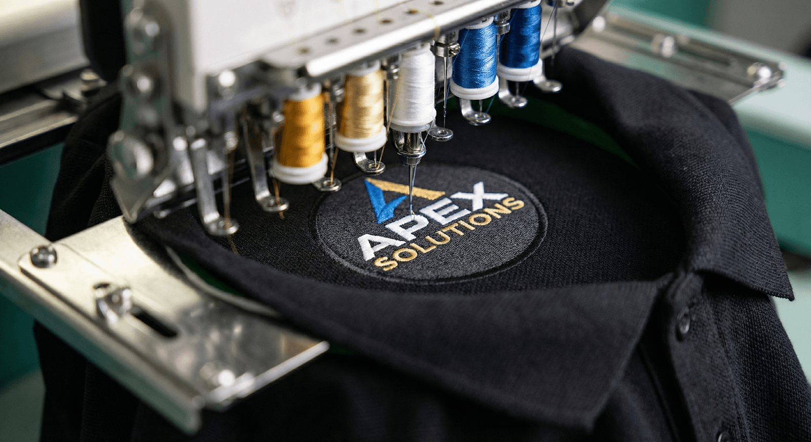 Broderie logo entreprise sur polo noir, gros plan machine à broder
